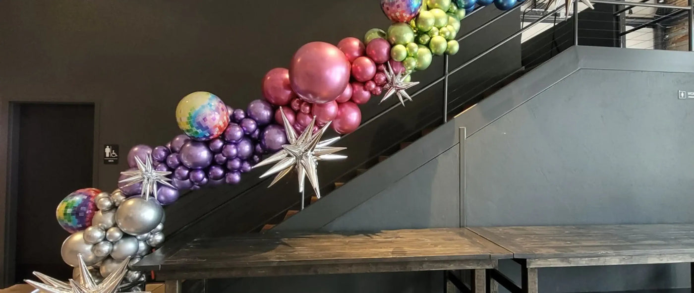 Colorful balloon arrangement on a staircase with a dark wall background
